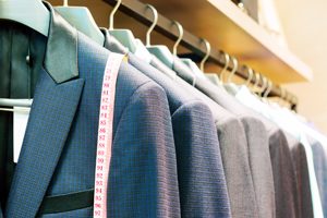 Row of men's suits hanging in closet.